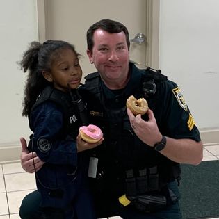 Sheriff eating donuts with little girl