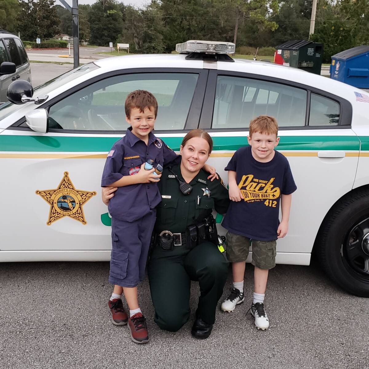 Sheriff hugging two children next to car